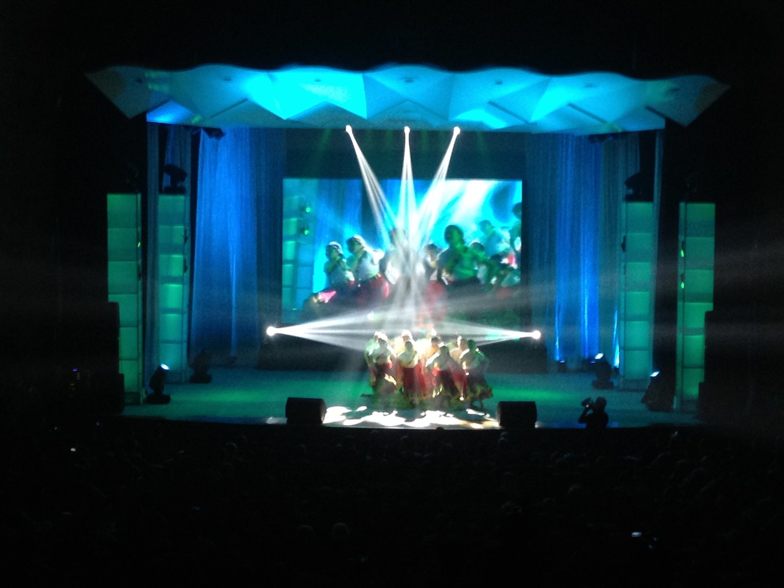 Dance performance framed by blue light and bright converging stage beams